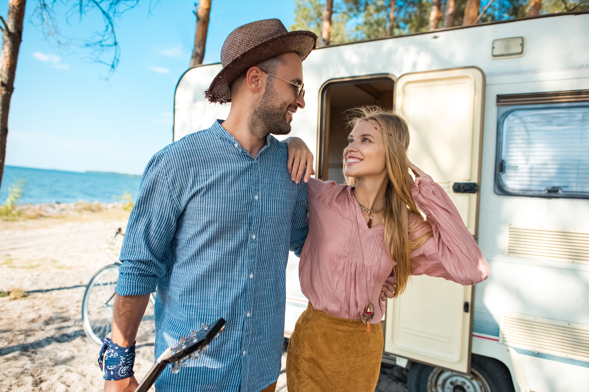 hippie couple hugging and walking near campervan